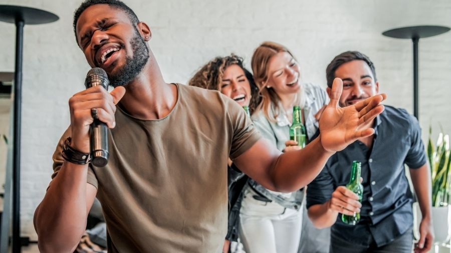 Group of friends enjoying karaoke together, laughing, drinking beer, and having fun.