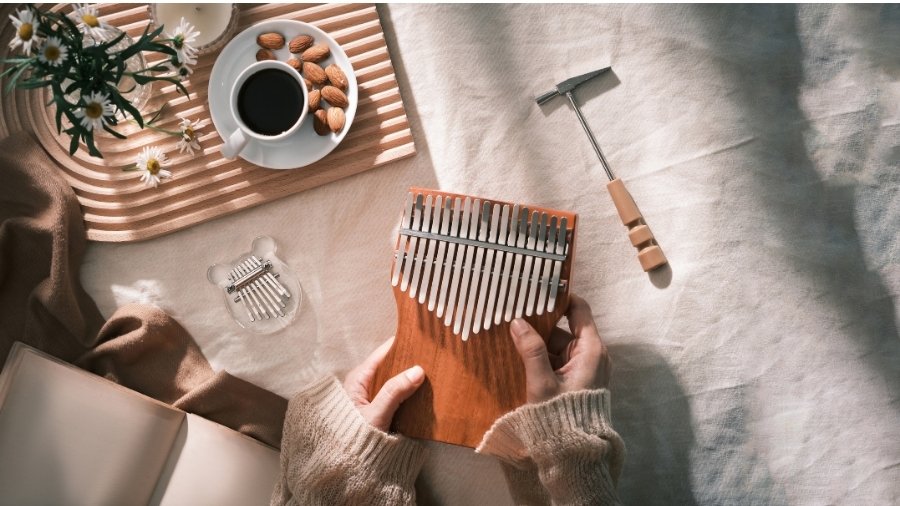 Woman holding a kalimba with a smaller kalimba and a kalimba tuner on a table