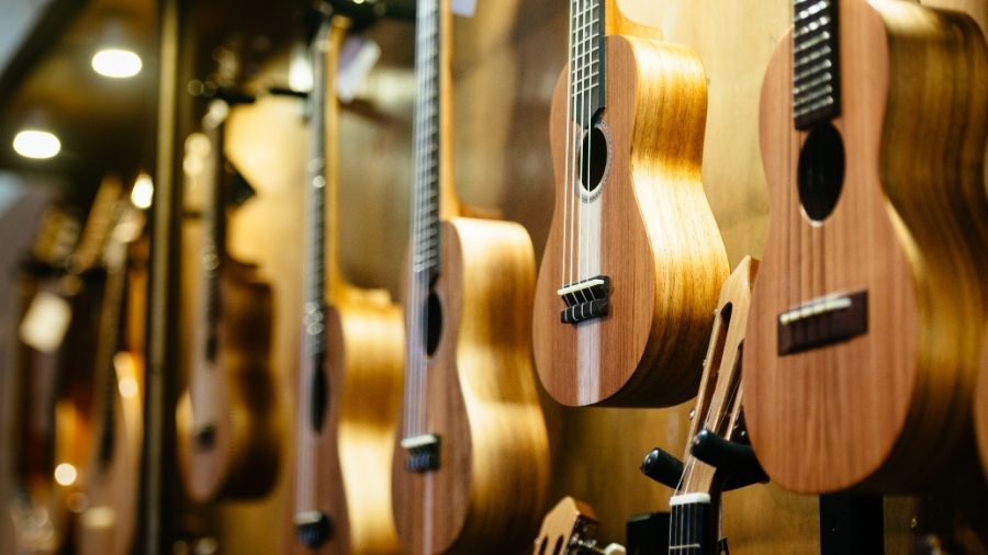 Close-up of multiple ukuleles displayed in a music store, with some instruments softly blurred in the background.