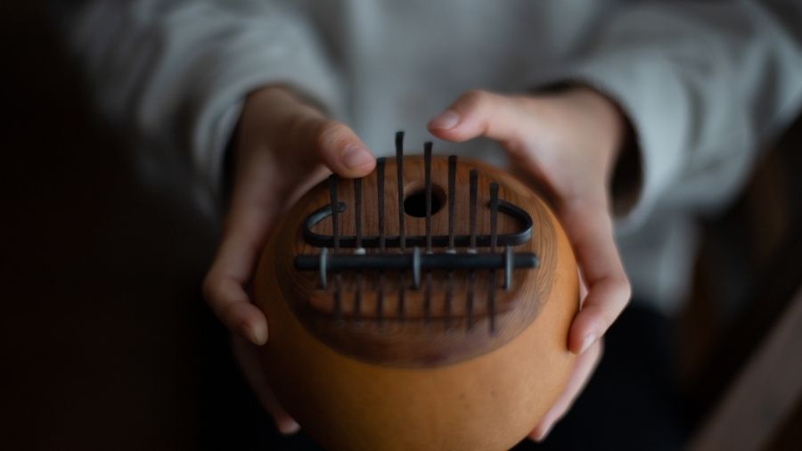 A girl holding and playing a kalimba with both hands.