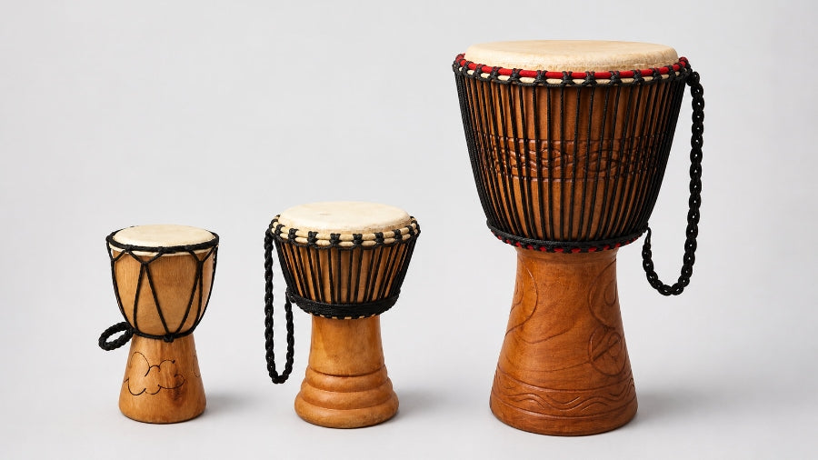 Small medium and large djembe drums on a light grey studio background
