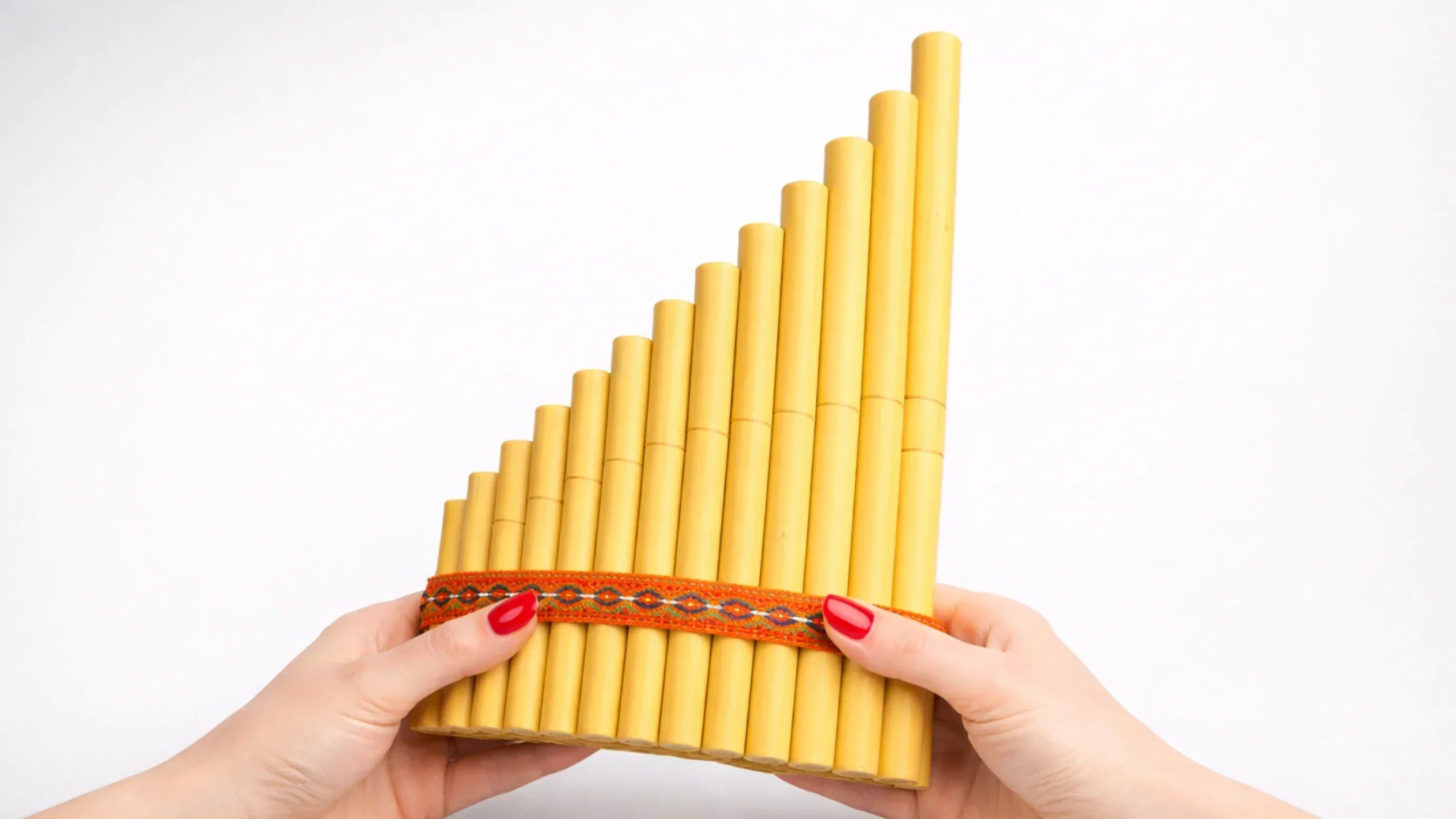 womans hands with red nails holding Siku pan pipes
