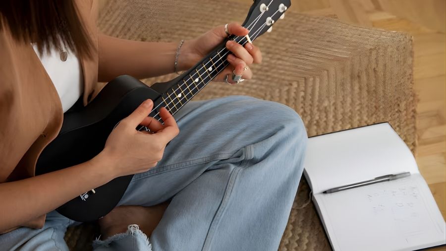 A woman demonstrating ukulele vibrato by gently rocking the string with her finger.