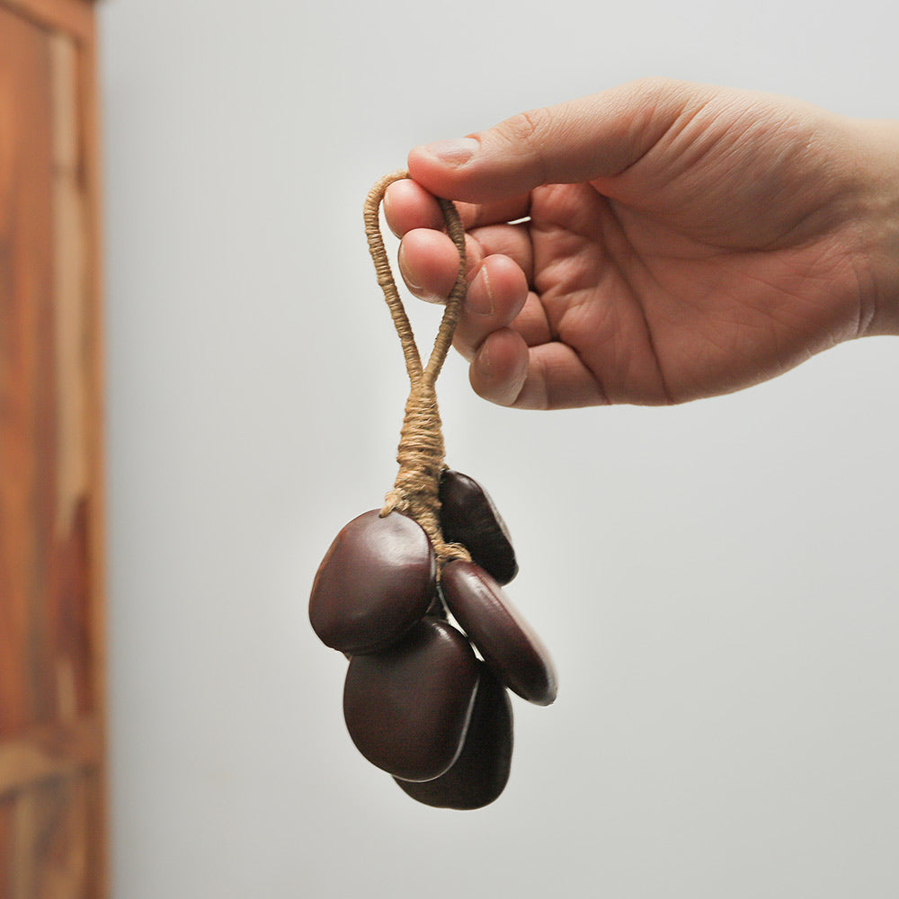 Close-up of Agba jute shaker held in hand, showing scale and length with a hanging view.