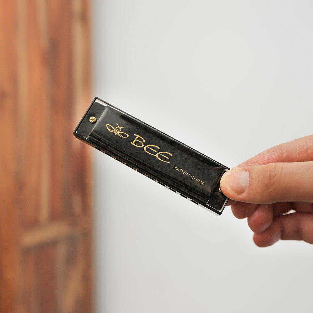 Bee design harmonica metal instrument in hand for scale.