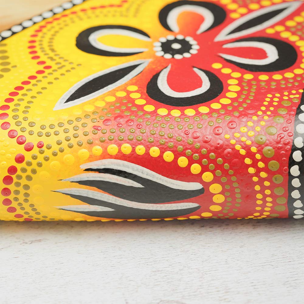 Close-up of the hand-painted yellow and orange design on a pocket didgeridoo, showcasing intricate details and vibrant colors.