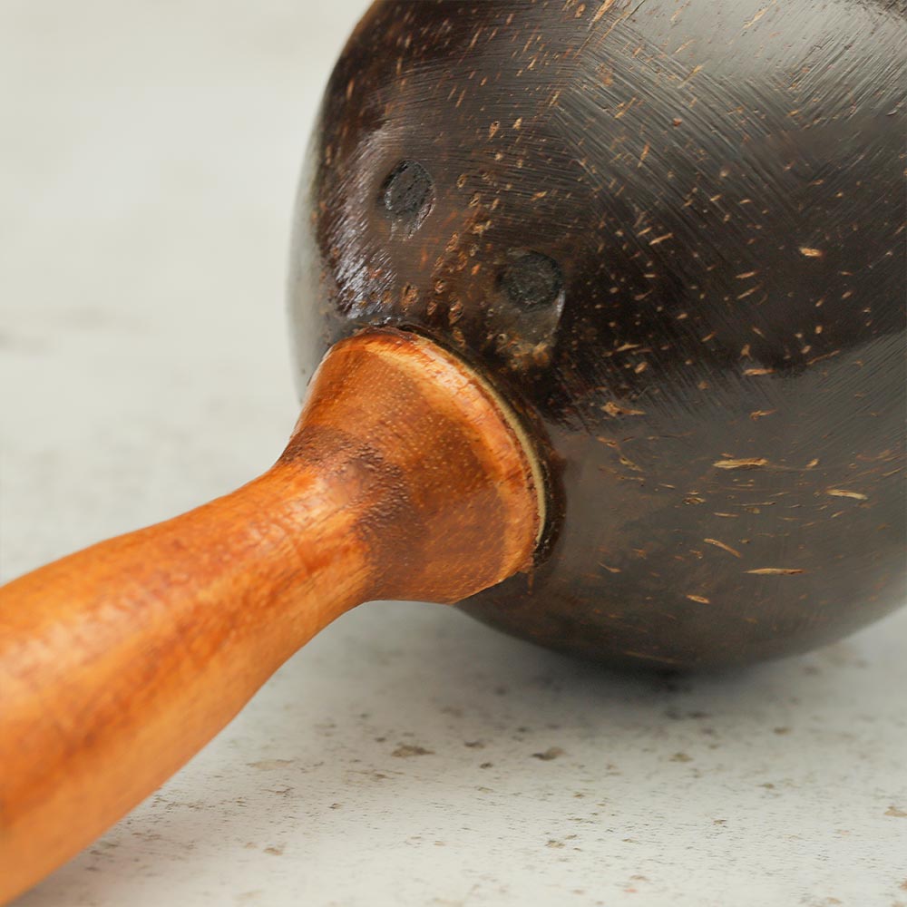 Close up of the coconut shell maraca showing the handle connected to the coconut
