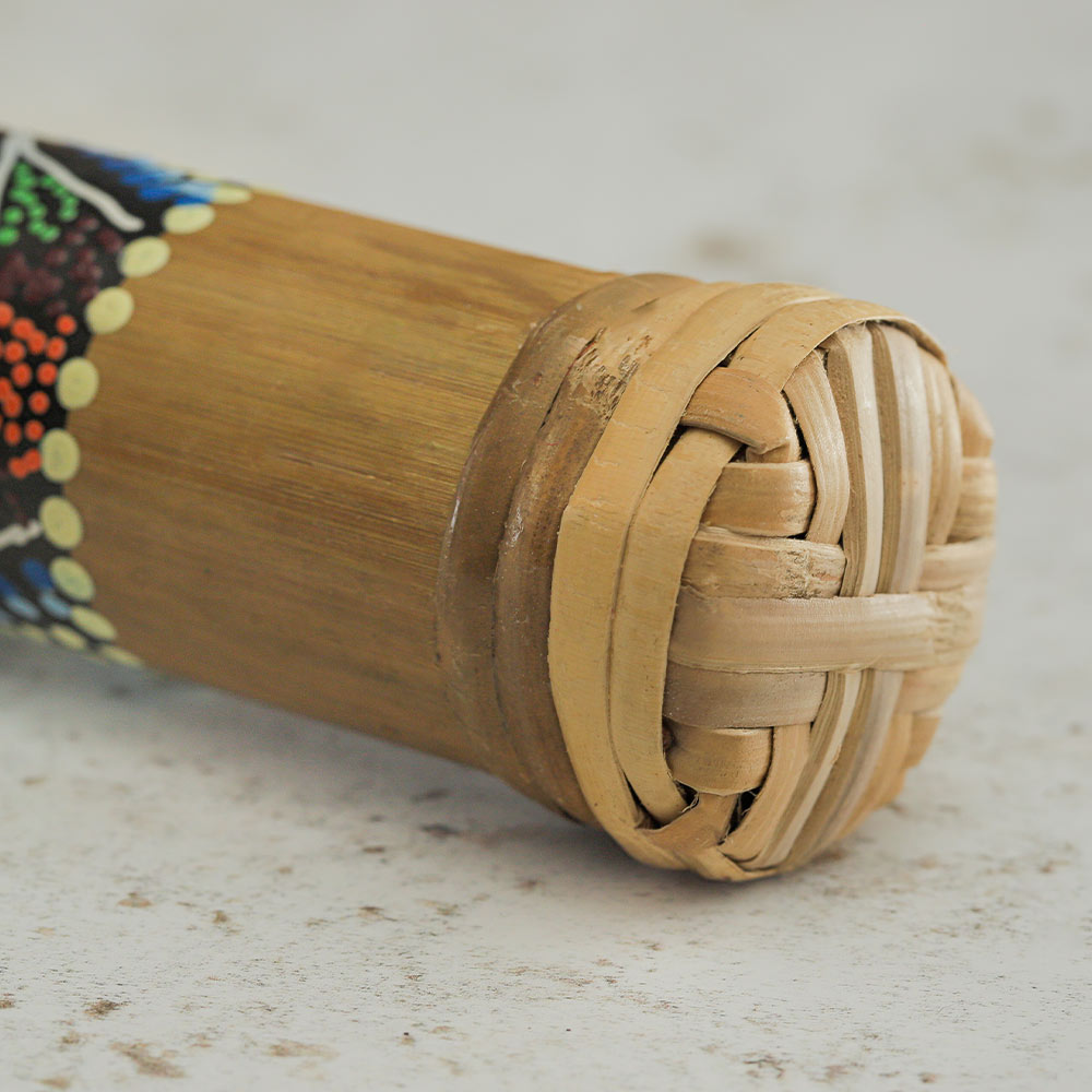 Bamboo rainstick close up showing the end of the instrument and hand painted design