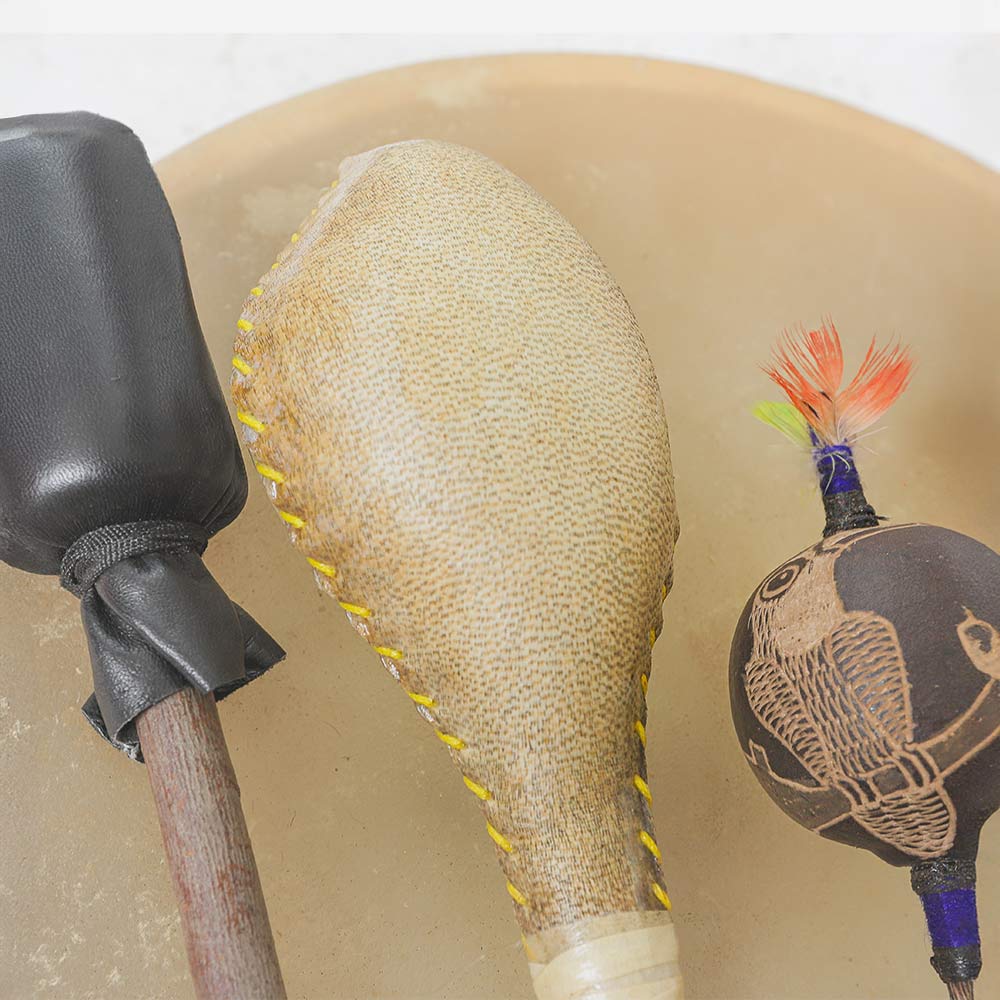 Close up of the terre animal hide shamanic shaker next to a beater and bird shipibo shaker on the khenji drum