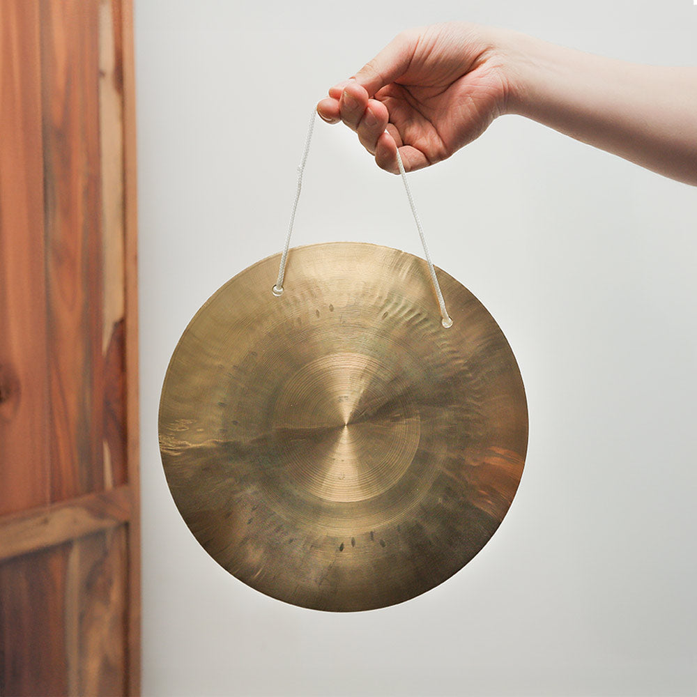 Feng Gong with string held in hand to show the size and scale of the hanging gong instrument.