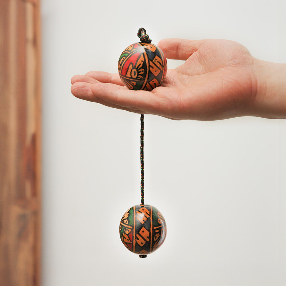 Geometric Kashaka shaker held in the hand to show its length and size for scale.