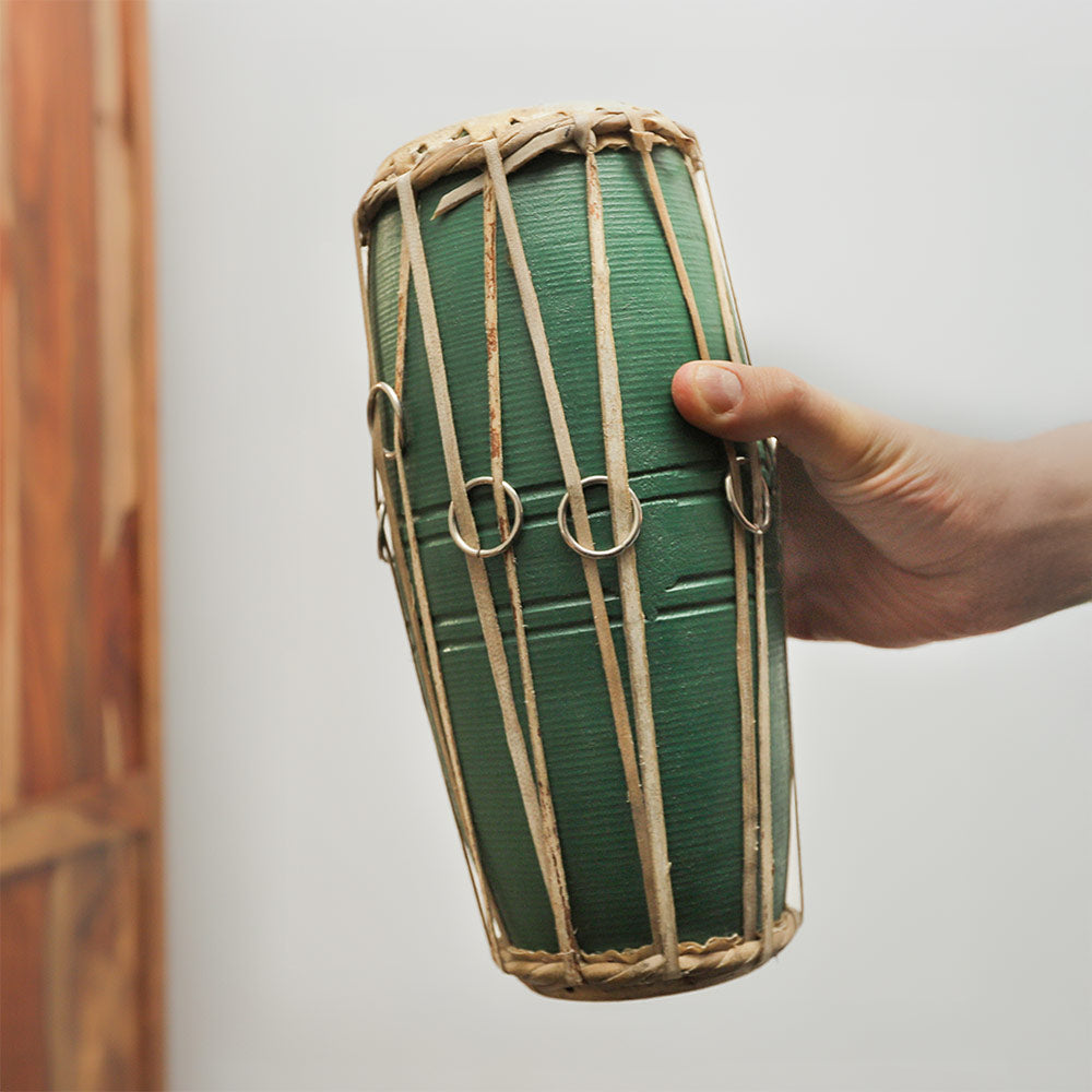 Green Nepalese Madal drum held in hand to show its size and scale.