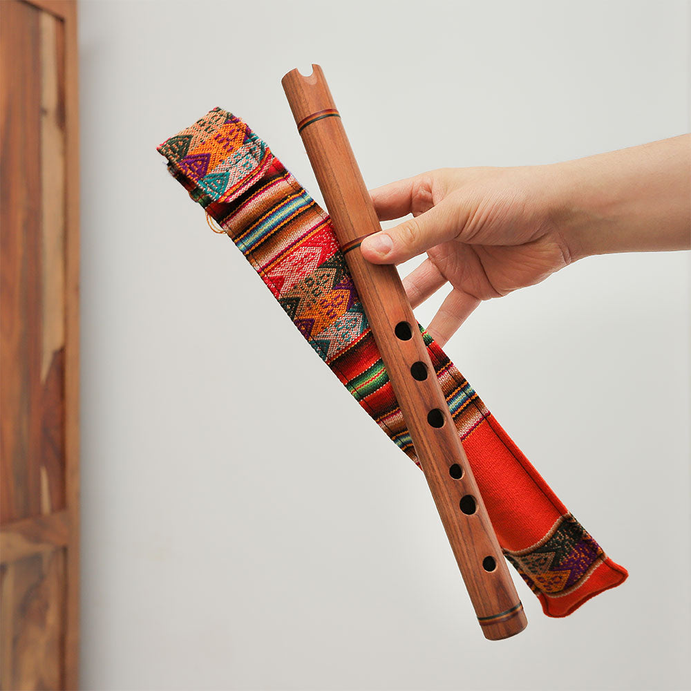 Close-up of a handmade wooden Andean quena flute whistle, featuring a fabric case for protection.
