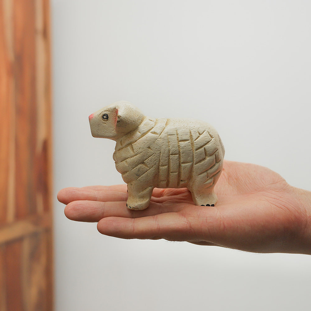 Handmade wooden sheep whistle held in hand to show its scale.