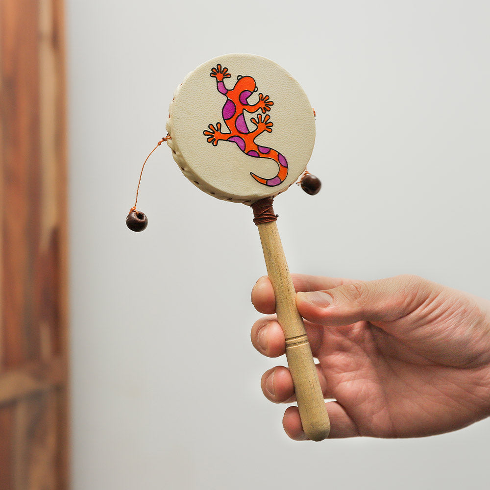 Close-up of a Jakarta monkey drum featuring a Gecko design, held in hand to show its size and scale.