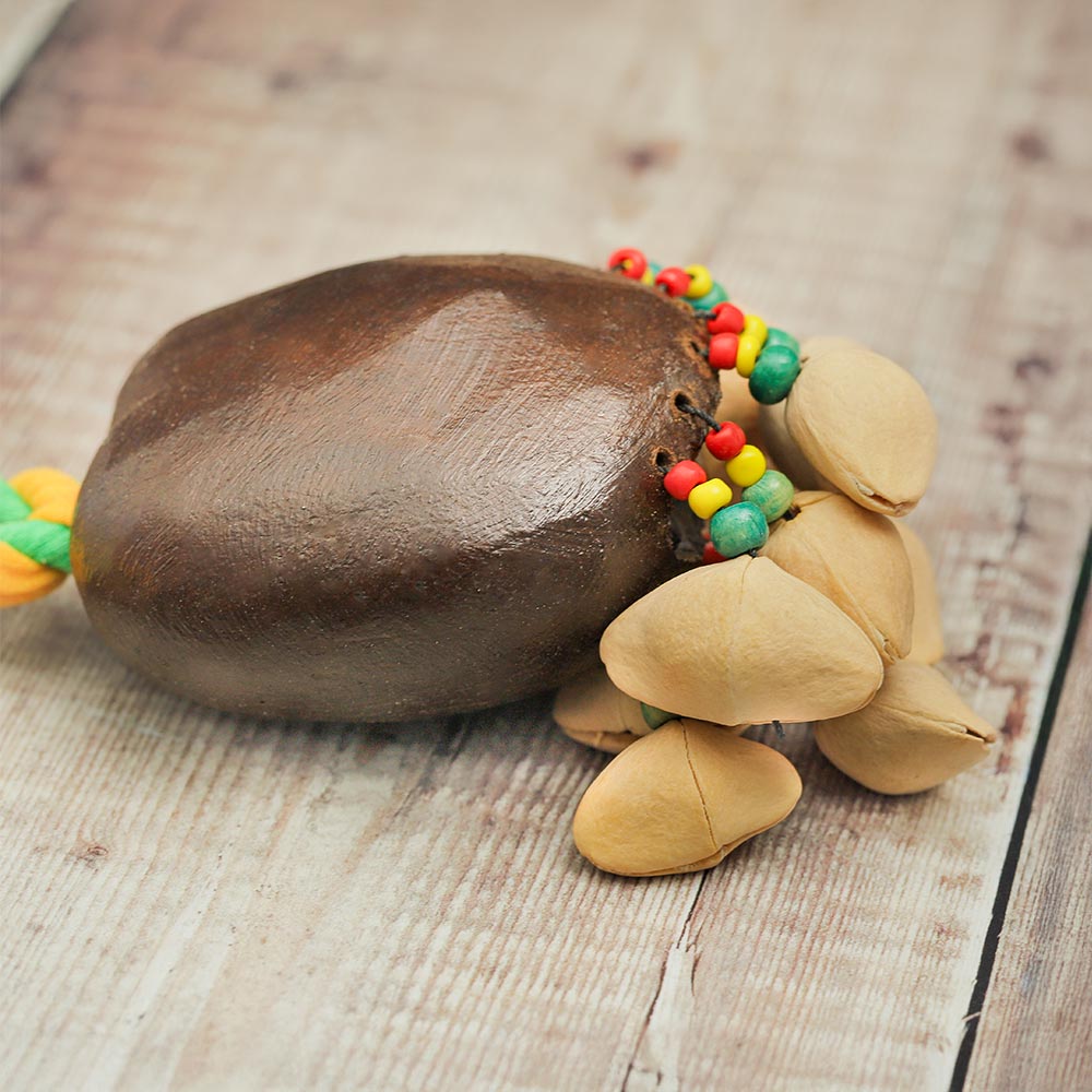 Close-up of the Lima rope nut shaker showing the natural husk, colourful beads, rope, and kesari seeds.