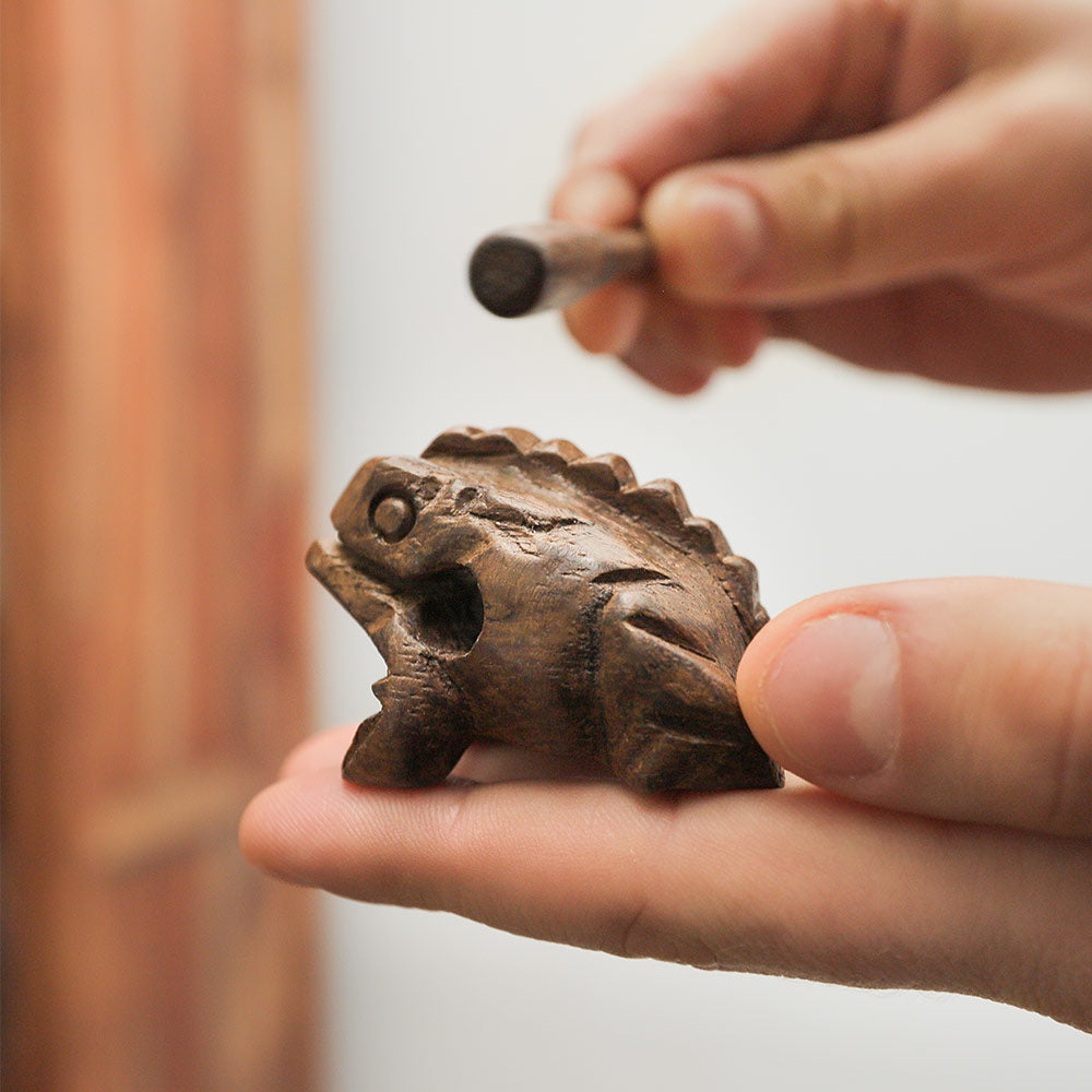 Mini croaking frog guiro held in hand to show scale size.