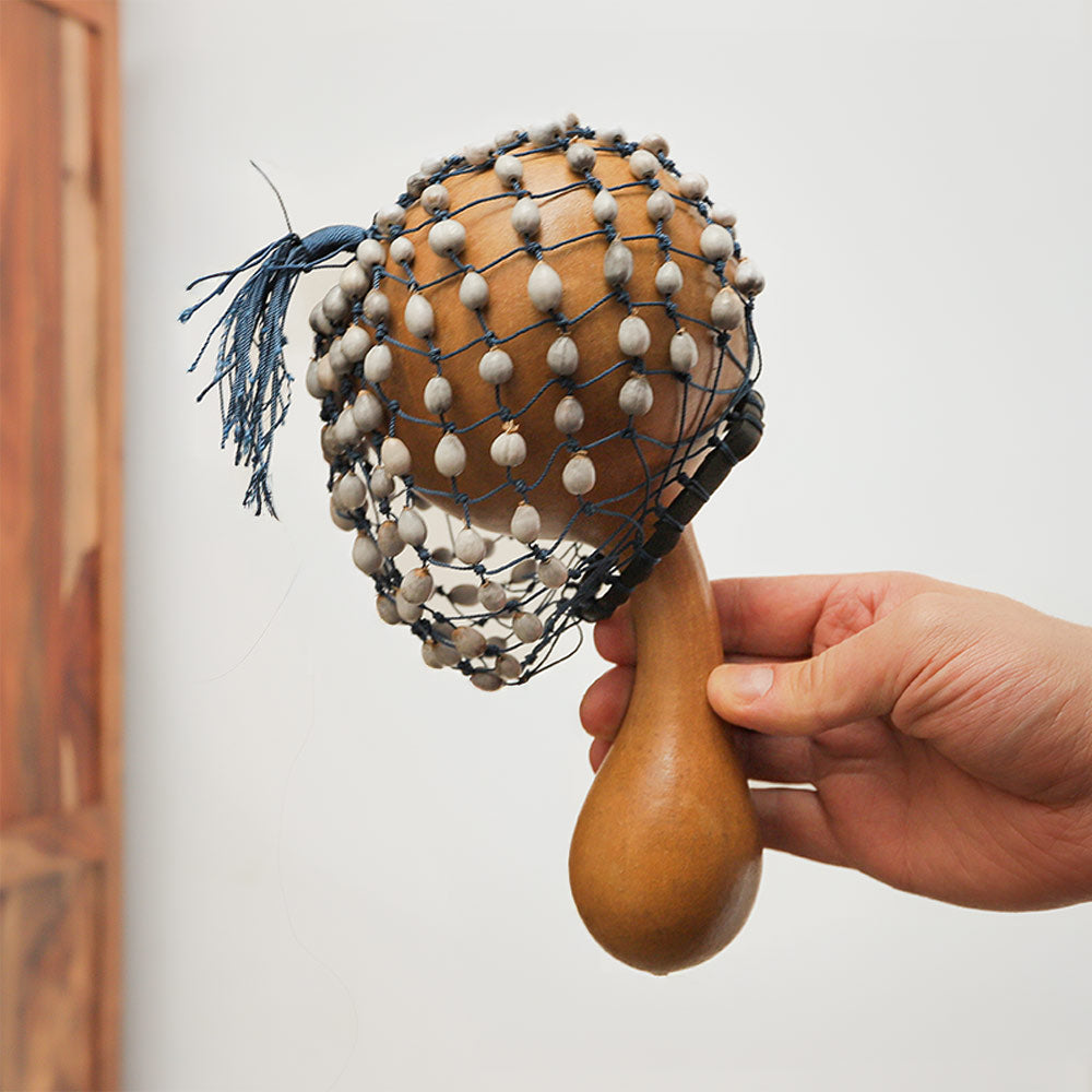 Natural African gourd cabassa shaker with beaded exterior, held in hand for scale, showcasing its size.