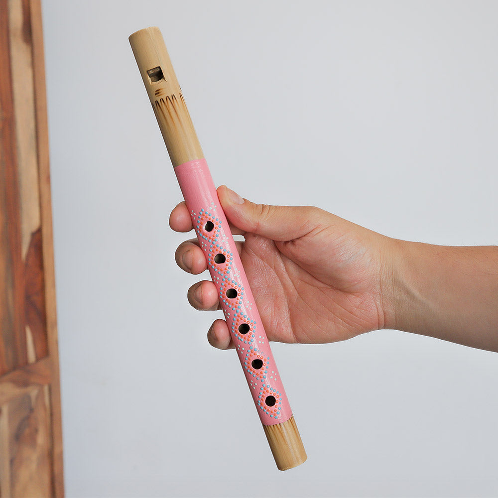 Pastel pink lembut painted bamboo recorder flute held in hand to show scale size.