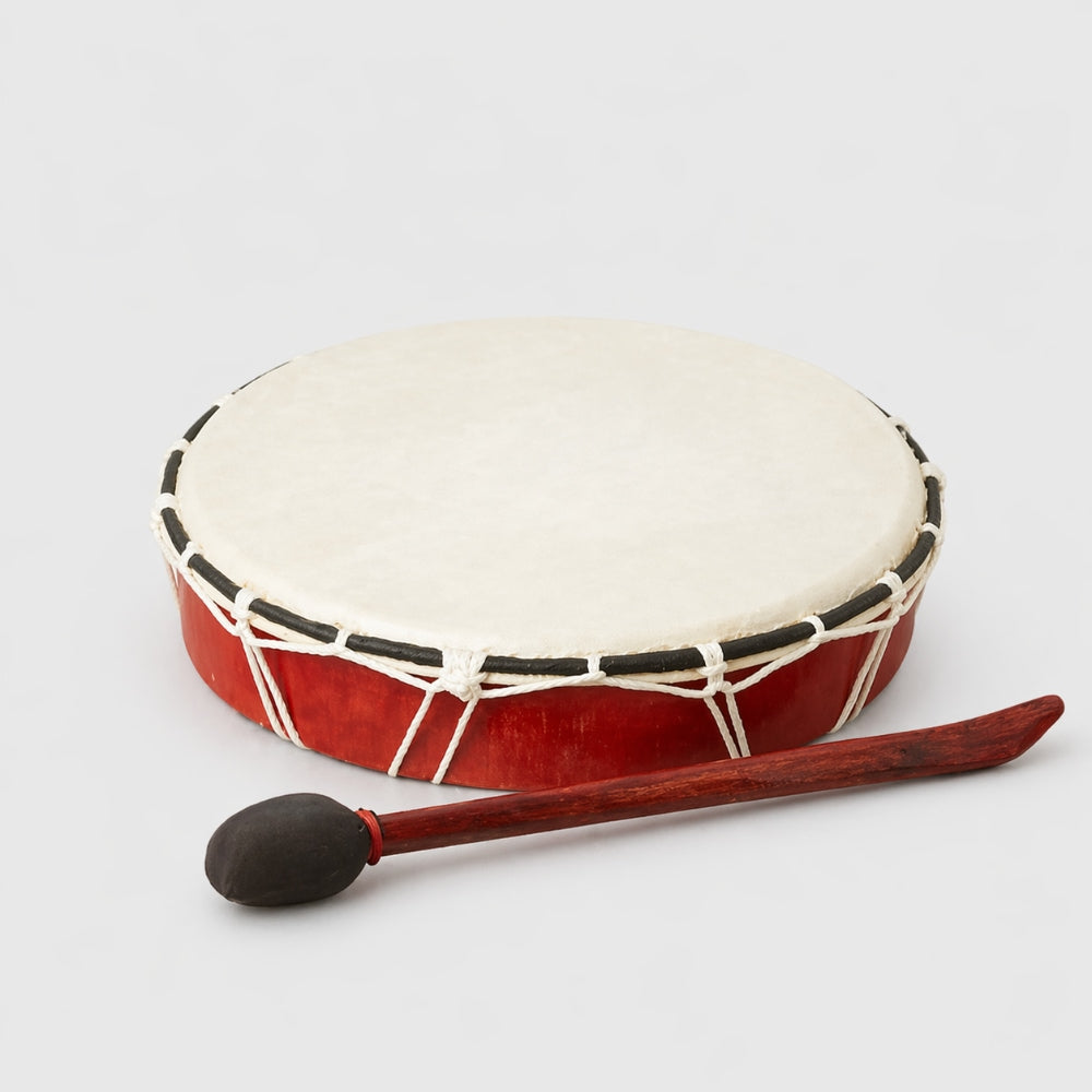 Wooden red plain medium shamanic drum from Indonesia with white rim and black accents on a light gray studio background