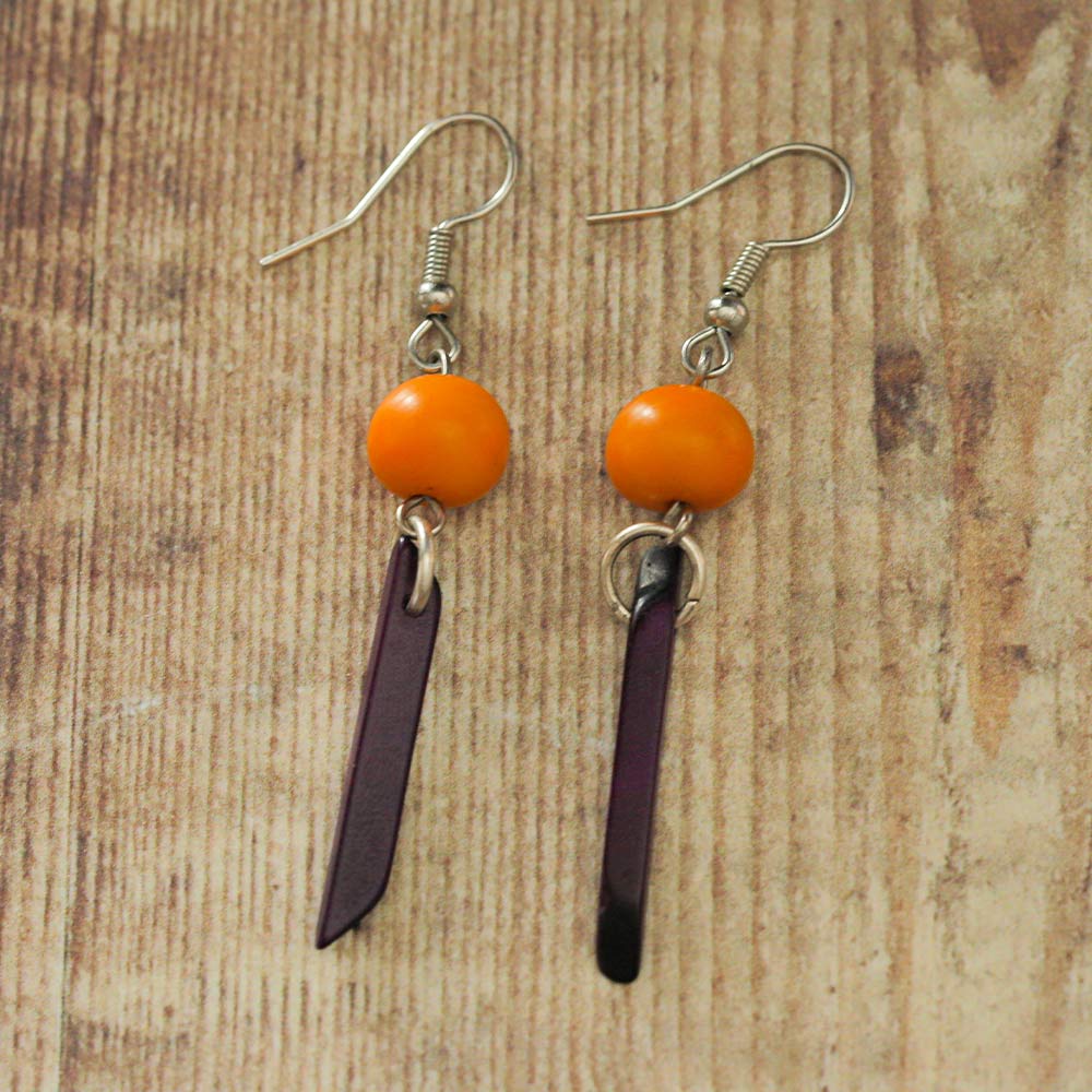 Purple and orange Tagua earrings on a wooden backdrop
