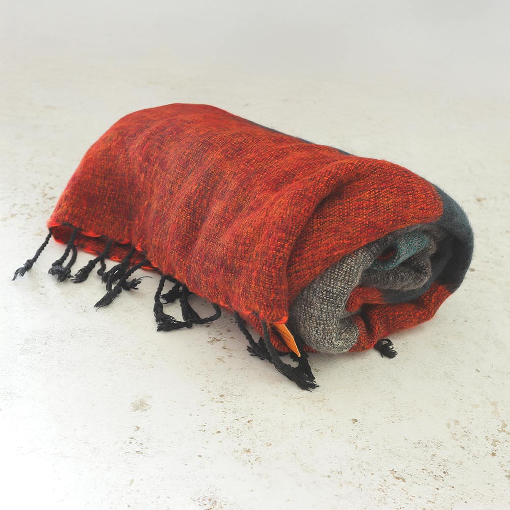 A red wool blanket with assorted colors, handloomed and made in Nepal, displayed on a light background.