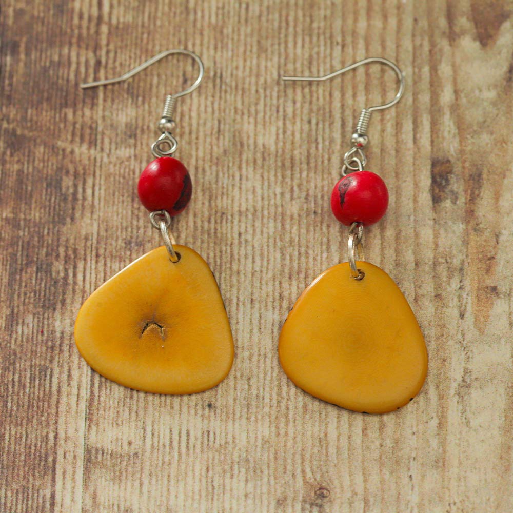 Yellowy orange and pinky red Tagua earrings on a wooden backdrop