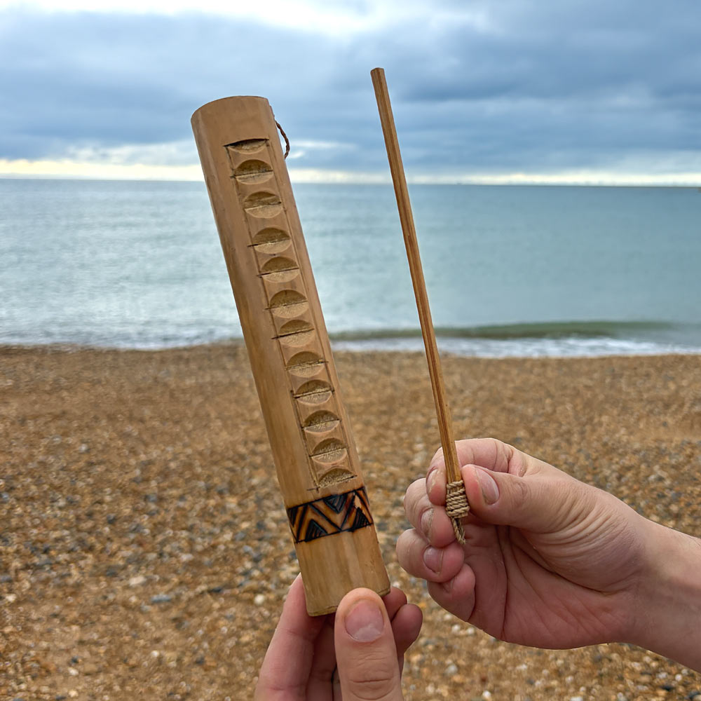 bamboo guiro with rasp in hand at the beach