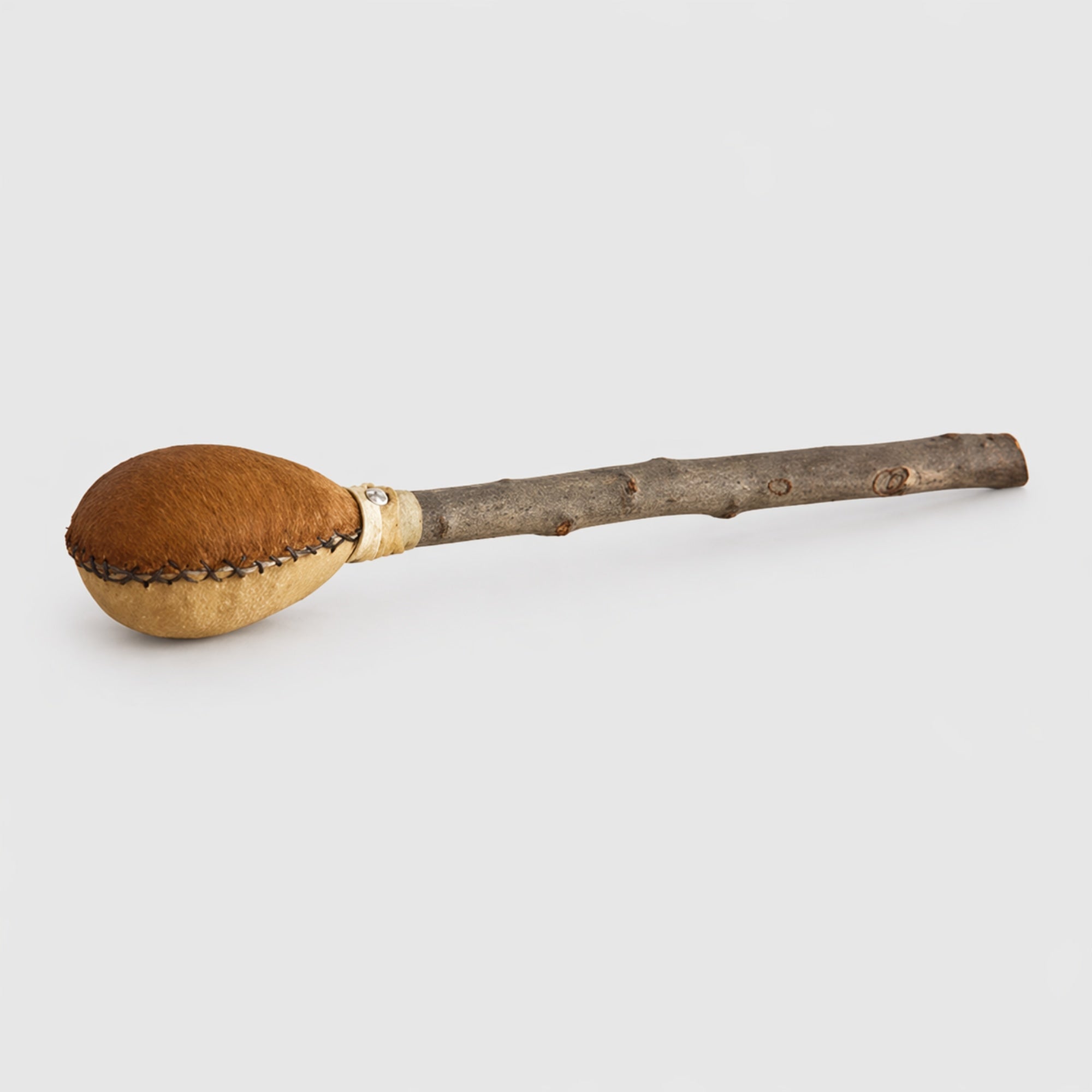Wooden cows hide shamanic shaker with a natural finish on a light gray studio background