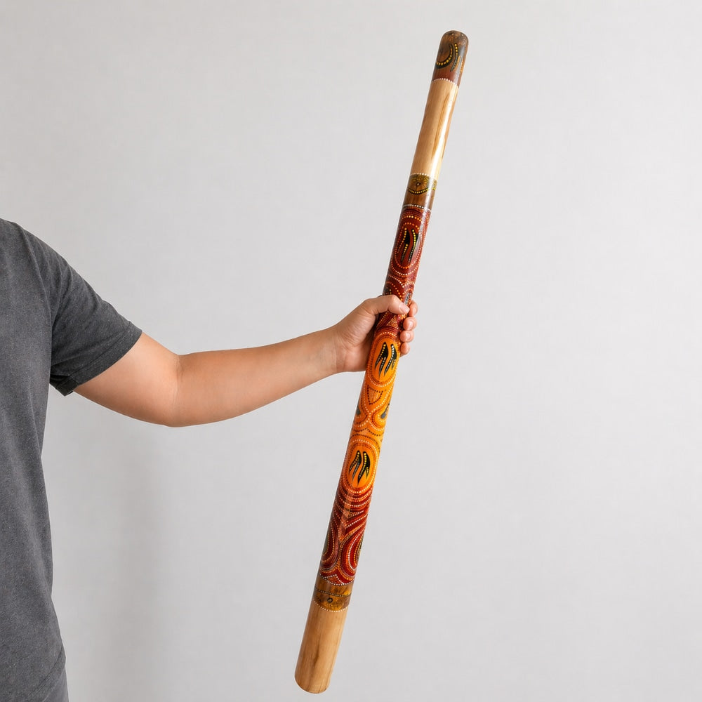 Hand holding painted melaya didgeridoo with light grey studio background