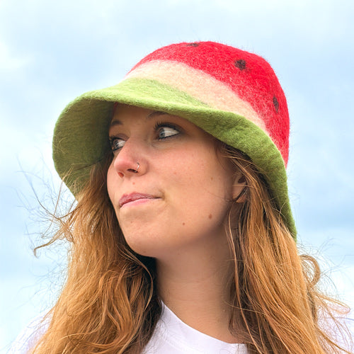 Person wearing a colorful bucket hat against a clear blue sky
