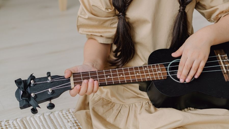 Girl holding a black ukulele.