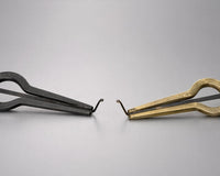Cast iron and brass jaw harps side by side on a grey studio background