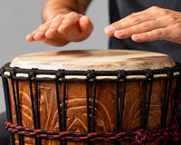 Hands playing a djembe drum in a studio