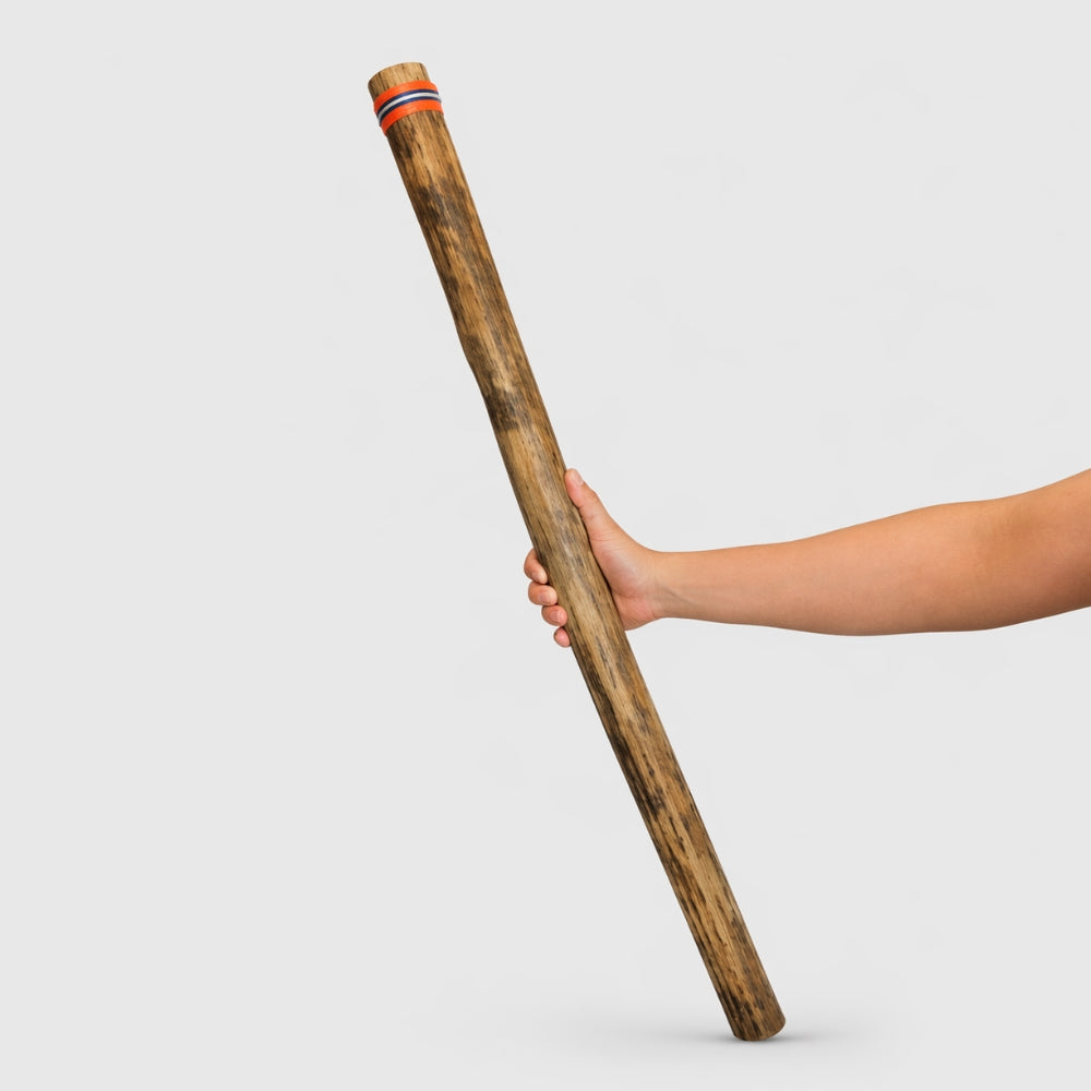 Hand holding a 100cm cactus rainstick for scale on a light gray studio background