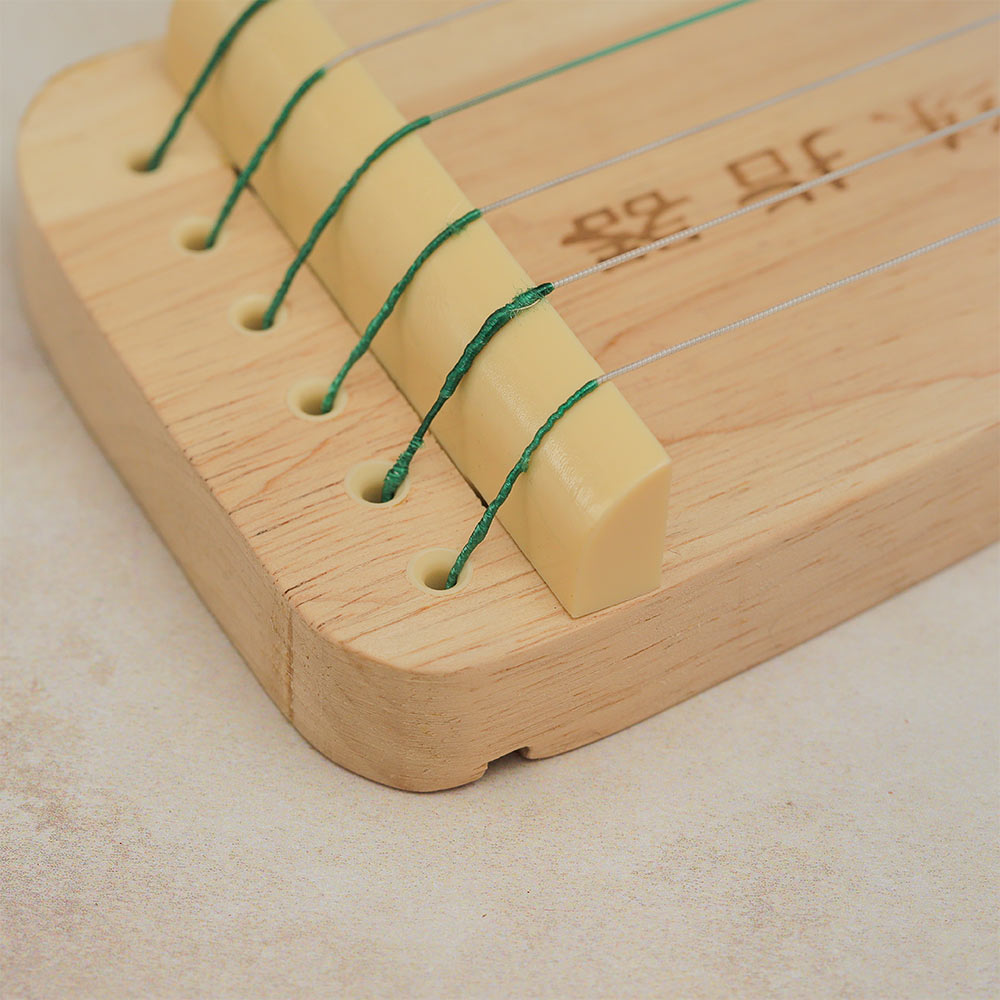 Close-up of the Guzheng Finger Trainer strings resting on the nut.