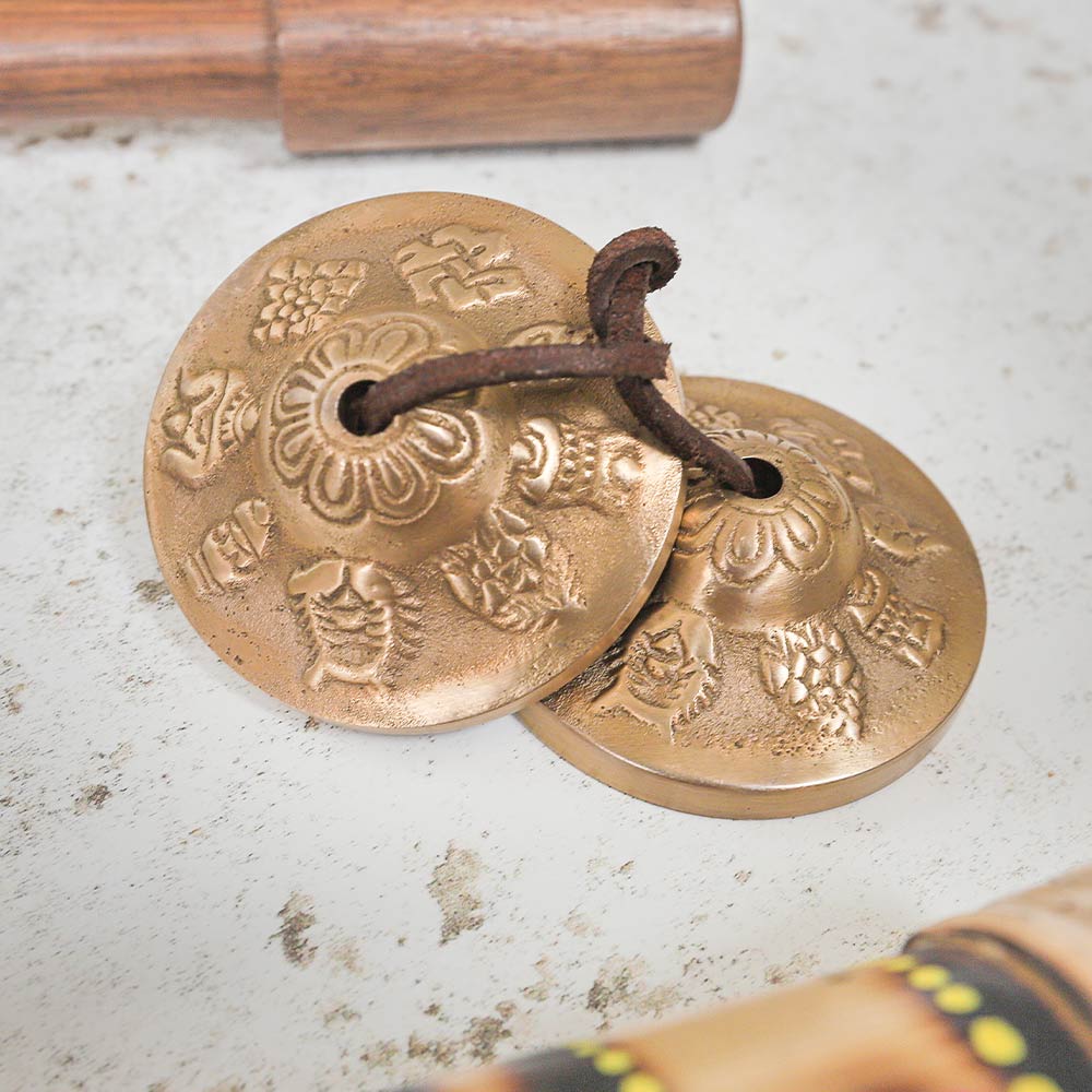 Close up of the Tibetan Tingcha Prayer bells with symbols alongside rainstick and beater