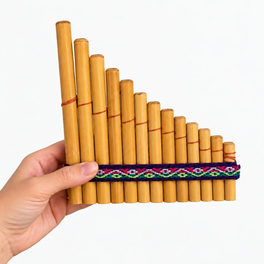 A hand holding a bamboo pan flute with a colorful woven fabric band around the middle, set against a plain light gray background.
