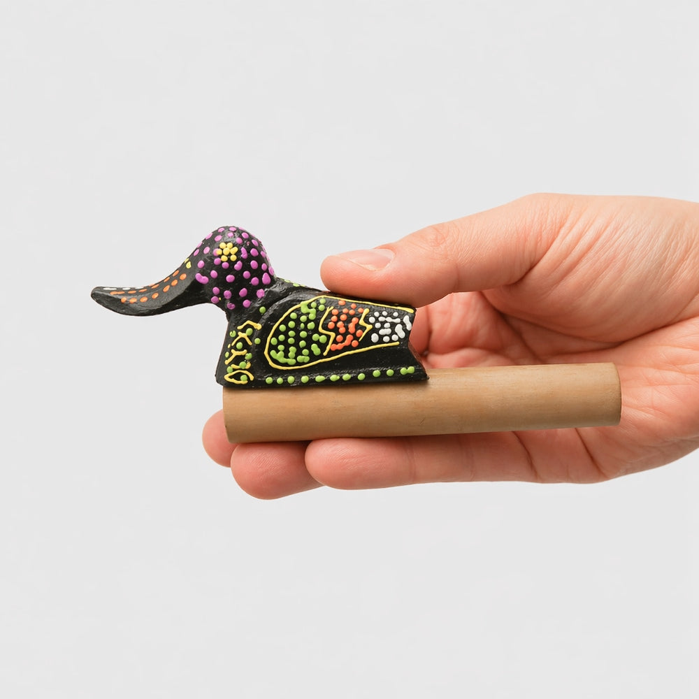 Handheld wood and bamboo duck quacker whistle with dot-painted design crafted in Indonesia on a light gray studio background