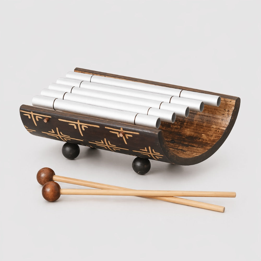 Wooden xylophone with metal bars and wooden mallets on a light gray background