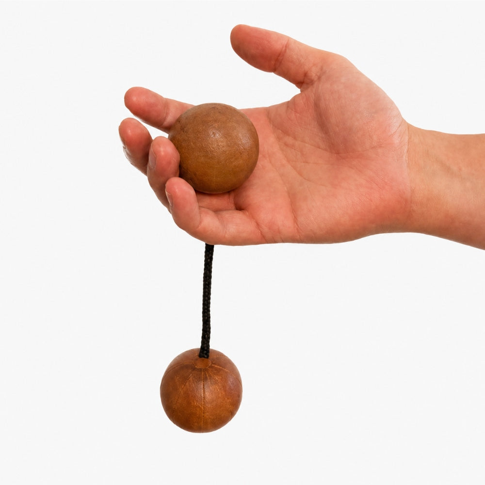 Gourd kashaka shaker dangling in hand to show scale on a light grey studio background