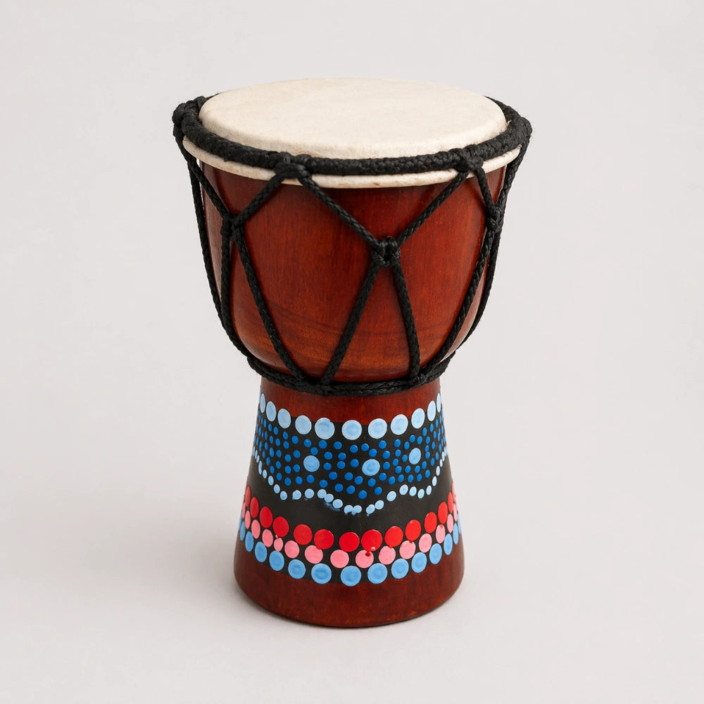 Hand holding a colorful drum on a beach with ocean in the background
