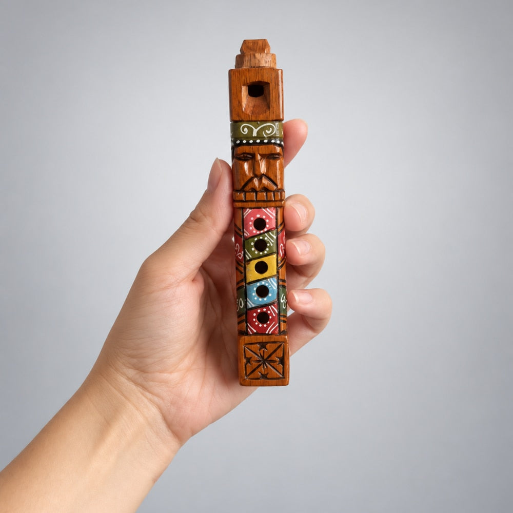 A hand holding a small carved wooden flute with colorful painted details, set against a plain light gray background.