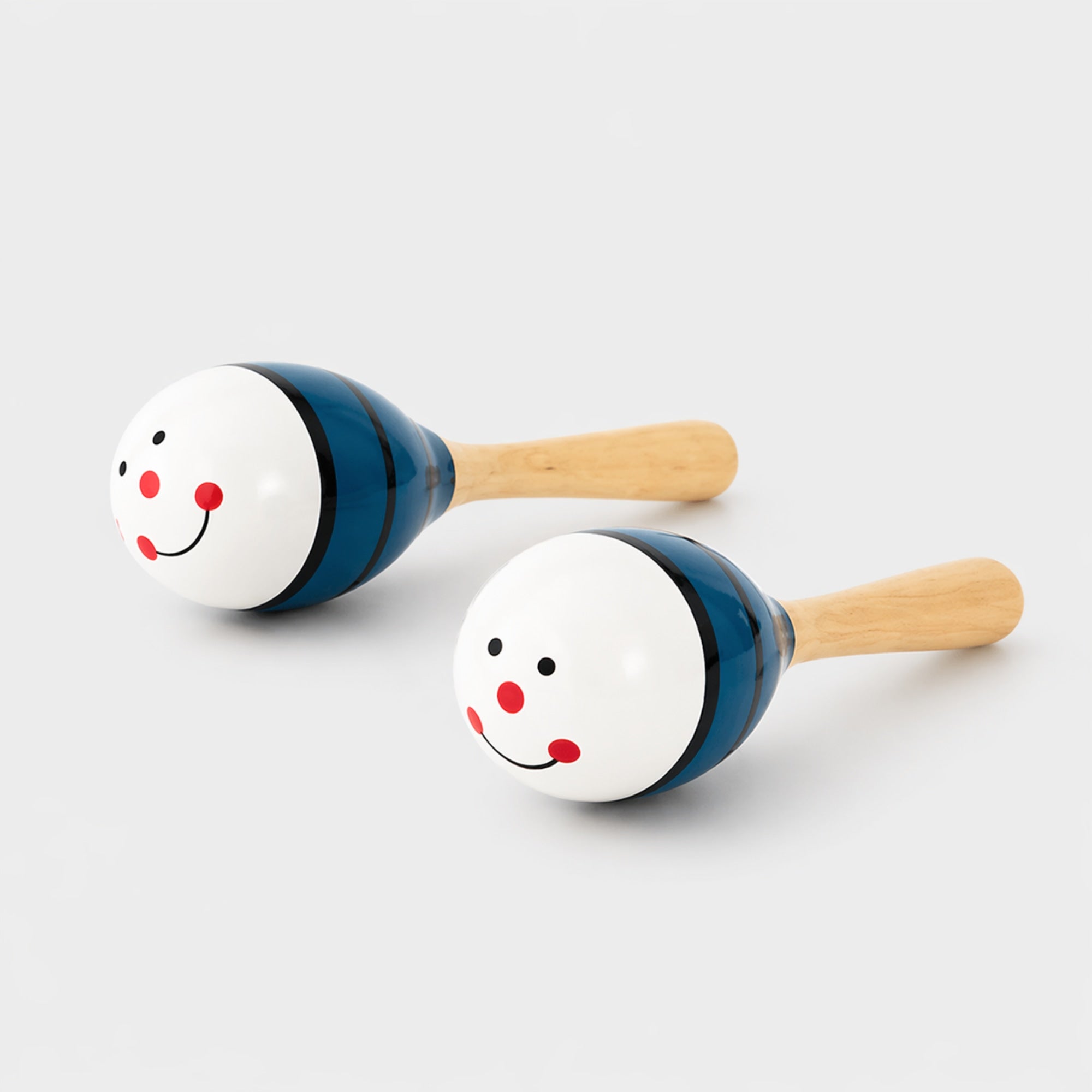Two wooden maracas with face designs on a light gray background